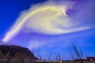 Via Lattea e nubi luminose notturne sopra le montagne islandesi