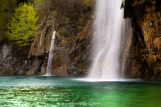 Cascata che si getta in un laghetto turchese nel Parco di Plitvice, Croazia