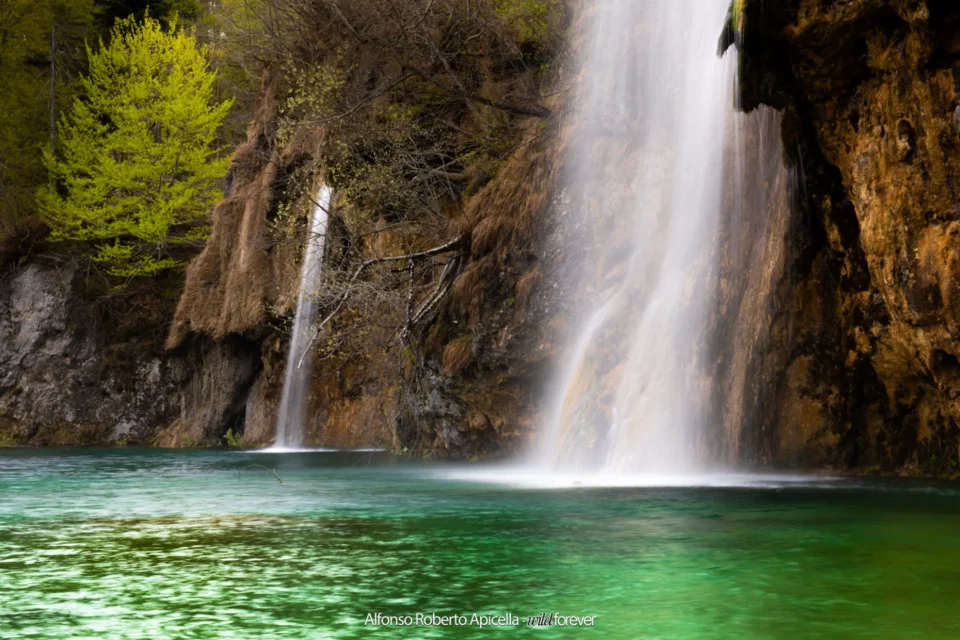 Cascata che si getta in un laghetto turchese nel Parco di Plitvice, Croazia